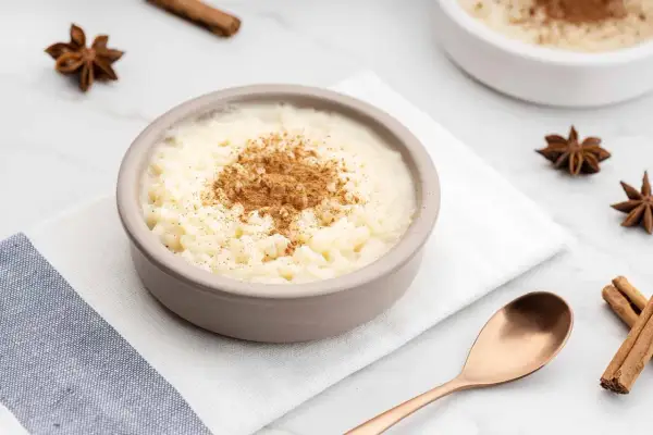 Un tazón de arroz con leche cremoso, espolvoreado con canela. ¿Quién inventó el arroz con leche? Un misterio delicioso.