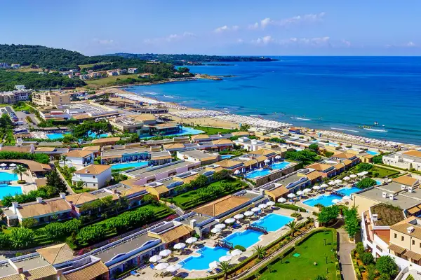 Idealne wakacje na Peloponezie: rozległy kompleks hotelowy z basenami i plażą nad turkusowym morzem.