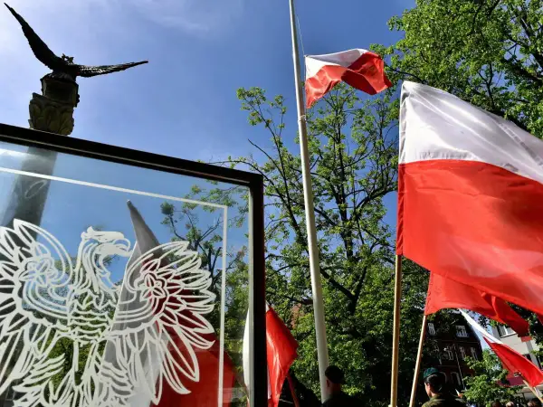 Orzeł biały i polskie flagi na tle nieba. Czy 3 maja można pracować? To pytanie zadają sobie Polacy w święto Konstytucji.