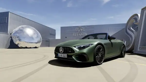Zielony Mercedes SL 63 AMG na tle budynku z napisem "The Star is Reborn" i futurystyczną rzeźbą.