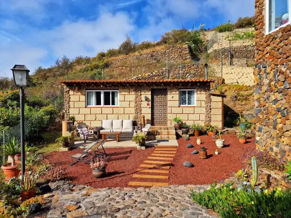 Acogedora casa rural de piedra, rodeada de plantas y con un camino de madera que lleva a la entrada. Un lugar perfecto para disfrutar de la tranquilidad de el escobonal.