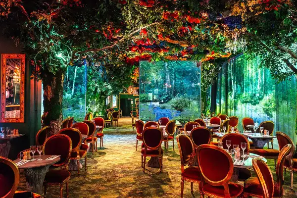 Un restaurant gastronomique féerique, avec des tables dressées sous une voûte de verdure luxuriante et des décors de forêt enchantée.