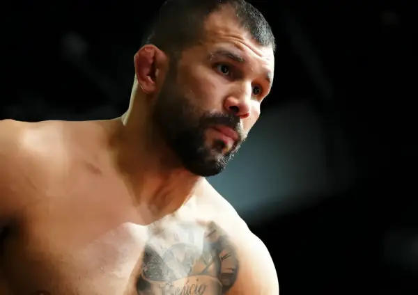 Rodolfo Vieira, en MMA-fighter med intensiv blick och tatueringar på bröstet, förbereder sig för strid.