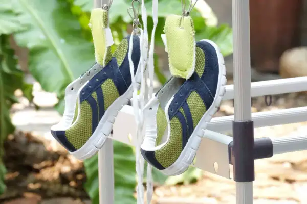 Scarpe sportive verdi e blu appese ad asciugare all'aperto, un metodo efficace per capire come lavare le scarpe dentro e farle tornare come nuove.