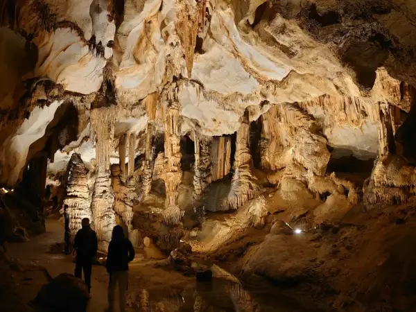 Dwie osoby zwiedzają imponujące jaskinie w Polsce, podziwiając stalaktyty i stalagmity.