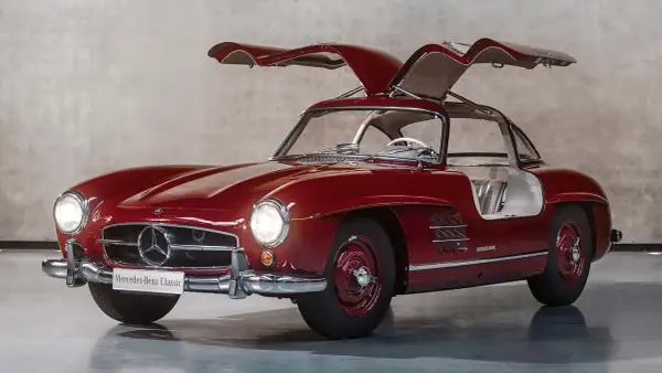 Czerwony Mercedes 300 SL z otwieranymi do góry drzwiami, prezentujący swoje klasyczne piękno.
