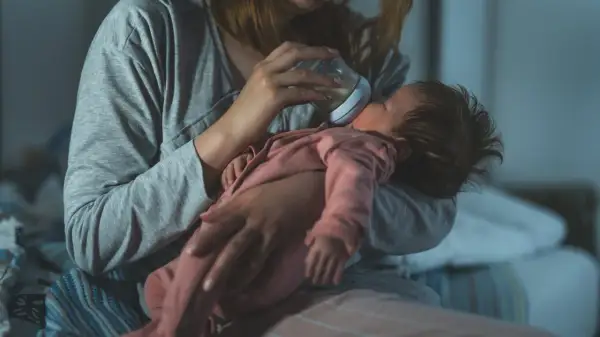 Mama karmi butelką noworodka, dbając o jego potrzeby. Mały brzuszek mieści niewielką ilość mleka, co odzwierciedla pojemność żołądka noworodka.