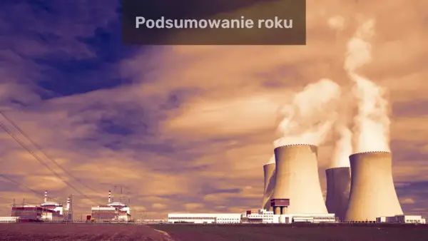 Podsumowanie roku w fizyce jądrowej: elektrownia z chłodniami kominowymi i budynkami przemysłowymi na tle dramatycznego nieba.