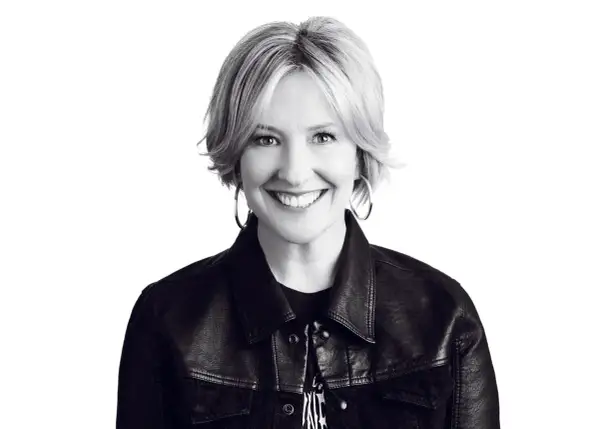 Uśmiechnięta Brené Brown w skórzanej kurtce, uosobienie odwagi i autentyczności.