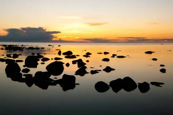 Solnedgång över havet med stenar i förgrunden. Perfekt för gotland tips.