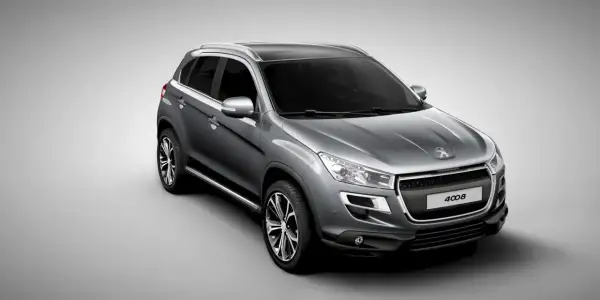 Szary crossover Peugeot 4008 z czarnym dachem i srebrnymi relingami, widok z przodu i z boku.
