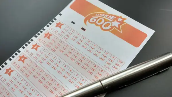 Długopis leży na kuponie lotto "Szybkie 600", gotowy do zaznaczenia liczb. Dowiedz się, jak sprawdzić numery lotto i czy masz szansę na wygraną!