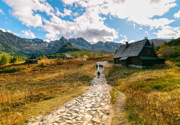 Kamienna ścieżka prowadzi do górskich chat. W oddali majestatyczne Tatry. To piękne zakopane atrakcje.