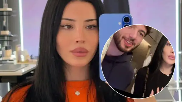 Kobieta z długimi czarnymi włosami, przypominająca czarodziejkę Liz, robi selfie. W tle widać mężczyznę.