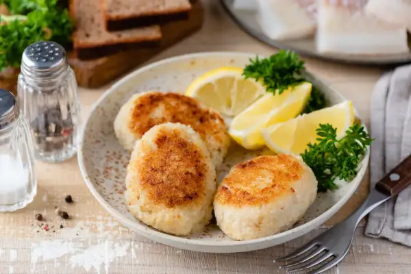 Filetti di merluzzo surgelati trasformati in gustose polpette, servite con spicchi di limone e prezzemolo. Perfette per ricette veloci e saporite.
