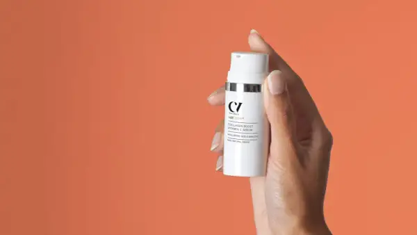 Hand hält Flasche mit "Collagen Boost Vitamin C Serum". Perfekt für Ihre Vitamin C Skincare Routine.