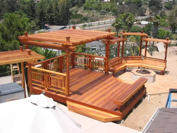 Terraza de madera de secuoya con pérgolas, bancos y hoguera. Un espacio ideal para disfrutar al aire libre.