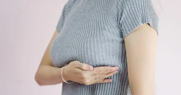 Kobieta bada swój sutek, odczuwając pieczenie. Dba o swoje zdrowie.