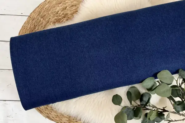 Dunkelblauer Denim-Stoff, aus dem Jeans gemacht sind, liegt auf einem Schaffell.