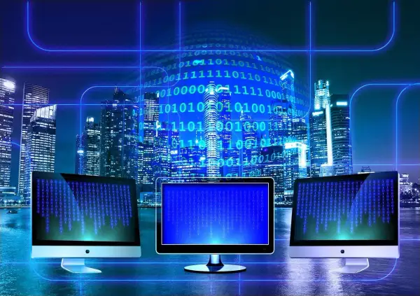 Trzy monitory wyświetlają kod binarny na tle nocnego miasta. W tle widać wieżowce i cyfrowy kod, symbolizujący technologię i sed linux.