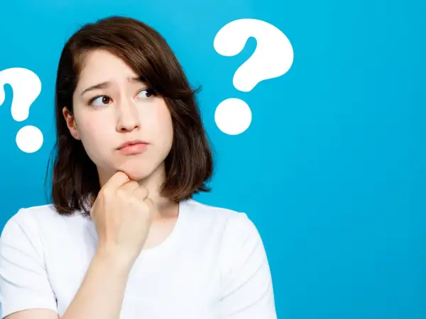 Junge Frau mit nachdenklichem Blick, die sich am Kinn kratzt. Mehrere Fragezeichen deuten auf ihre fünf head move-Gedanken hin.