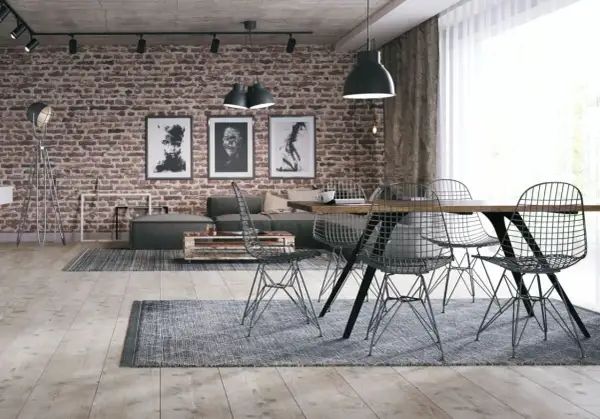 Surowy, betonowy sufit w stylu loft nadaje wnętrzu industrialnego charakteru. Ceglana ściana, grafiki i metalowe meble dopełniają ten surowy klimat.