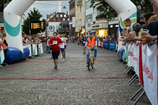 Läufer und Radfahrer beim Stadtlauf Bergisch Gladbach. Zuschauer jubeln am Streckenrand.