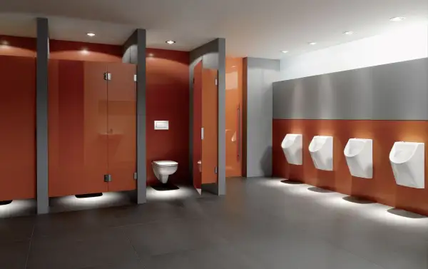 Moderne schul toilette mit orangen Kabinen und Reihen von Urinalen.
