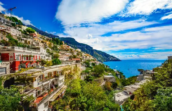 Positano, z czego słyną Włochy: kolorowe domy na zboczu góry, błękitne morze i łodzie.