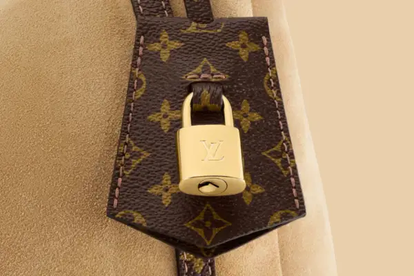 Złota kłódka z logo LV na brązowej skórze z monogramem Louis Vuitton.