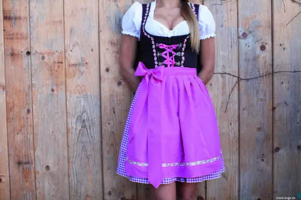 Dirndl mit pinkem Satinband-Schnürung und passender Schleife. Darunter ein karierter Unterrock.