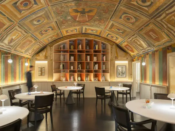 Interni eleganti con soffitto affrescato, libreria a vista e tavoli apparecchiati, un'atmosfera che evoca le stelle Michelin di Perbellini.