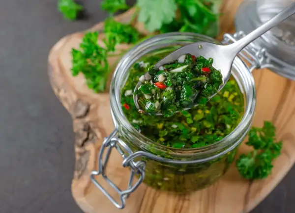 Sos chimichurri do mięsa z grilla przepis: świeża pietruszka, czosnek, chili i oliwa w słoiku. Idealny dodatek do grillowanych przysmaków.