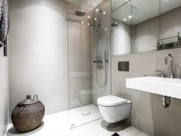 Moderno bagno senza finestra con doccia a filo pavimento, WC sospeso, lavabo minimalista e cesto in vimini.