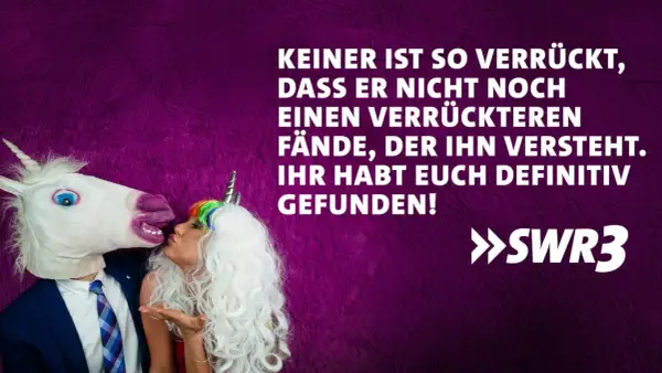 Ein Mann mit Einhornmaske küsst eine Frau mit Einhorn-Haarreif. Ein lustig-witziges Bild, das perfekt zum Hochzeitstag passt!