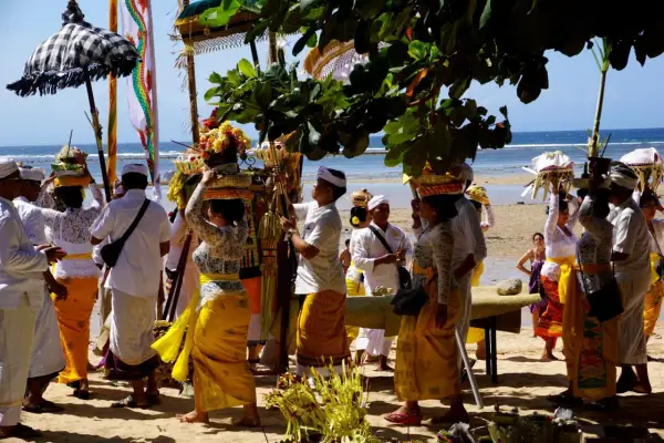 Uczestnicy procesji na plaży, niosący kosze z ofiarami, celebrują balijską religię.