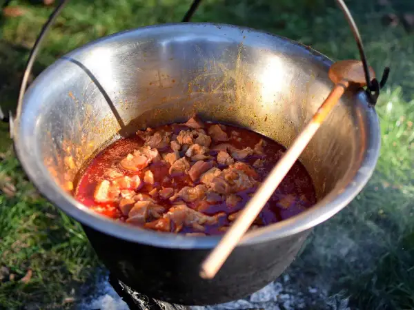 Pyszne dania z kociołka żeliwnego przepisy w akcji! Mięso dusi się w aromatycznym sosie, gotowe do podania.