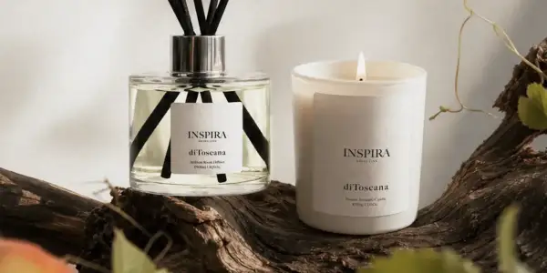 Dyfuzor i świeca Inspira "di Toscana" na tle drewna. Te zapachy tworzą własne, piękne histoires de parfums.