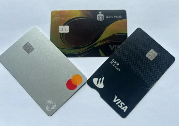 Trzy karty płatnicze: srebrna z logo Mastercard, czarna z logo Visa Credit Platinum i złota z logo Banku Polskiego.