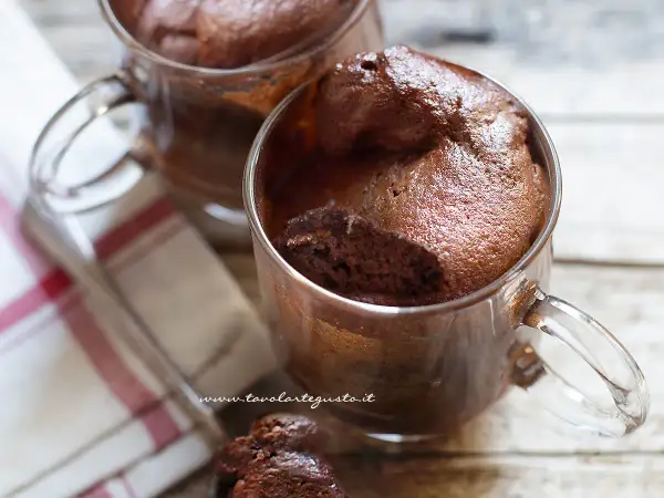 Due mug cake al cioccolato, soffici e golosi, serviti in tazze di vetro. Perfetti per una pausa dolce.