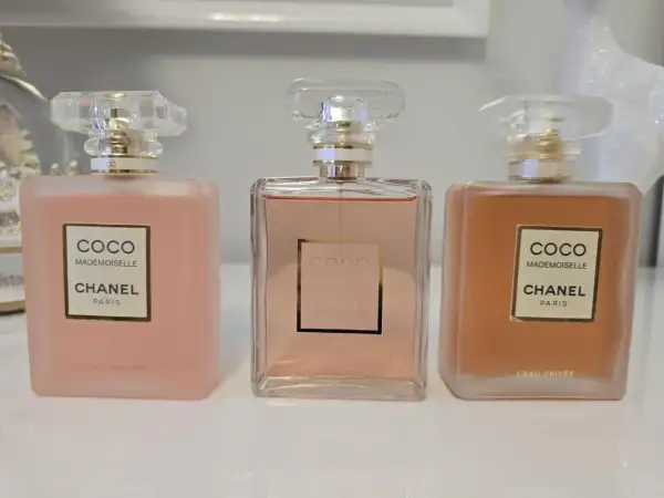 Trzy flakony Chanel Coco Mademoiselle L'Eau Privée w odcieniach różu i brzoskwini.