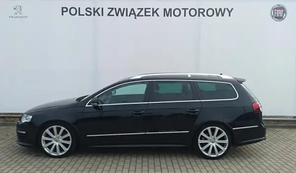 Czarny Volkswagen Passat kombi, model r36, zaparkowany przed budynkiem z logo Polskiego Związku Motorowego.