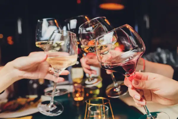 Ludzie wznoszą toasty kieliszkami z winem. Czy 5-HTP i alkohol to dobre połączenie?