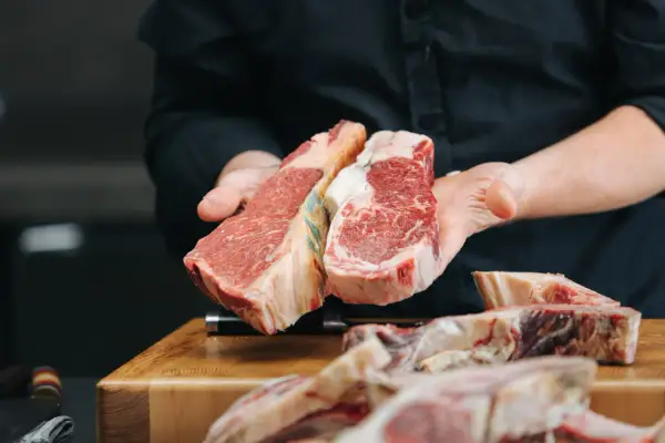 Manos sostienen dos cortes de ternera. La ternera es carne magra, ideal para una comida saludable y deliciosa.
