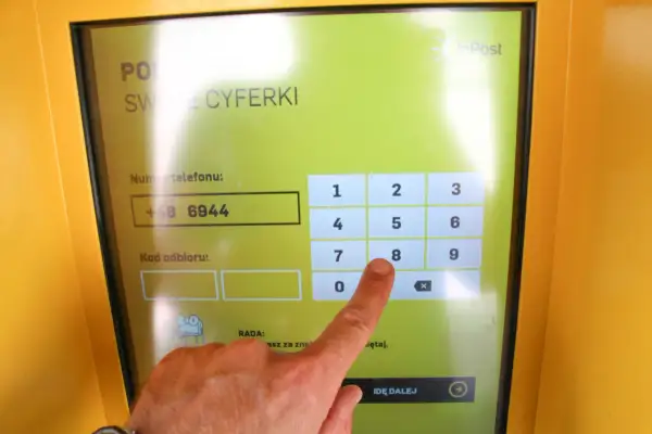 Palec wskazujący naciska cyfrę 8 na ekranie paczkomatu InPost.