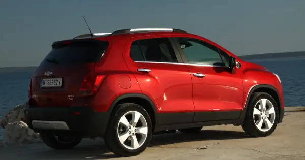 Czerwony Chevrolet Trax z tablicą rejestracyjną W 88762 V stoi nad morzem.