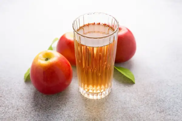 Glas mit Apfelsaft und Äpfeln. Über Apfelessig trinken Nachteile nachdenken.