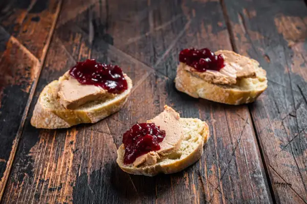 Trois toasts de pain de campagne garnis de foie gras et de confiture de fruits rouges. Un délice qui évoque le foie gras origine.