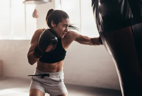 Focused female boxer practices double end bag drills, her punches a blur of motion.