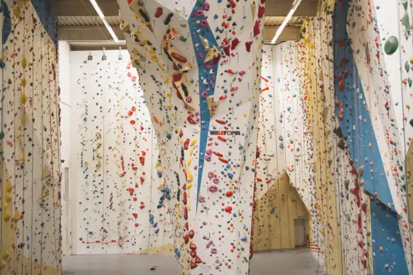 Bunte Griffe zieren die hohen Wände einer 2t Kletterhalle. Ein Paradies für Kletterfans, das zum Erklimmen einlädt.